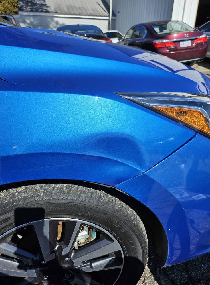 Before: fender dent on blue sedan in Central North Carolina