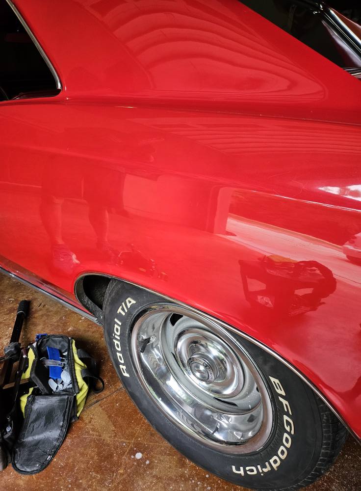 After: fender dent removed with PDR on classic red vehicle